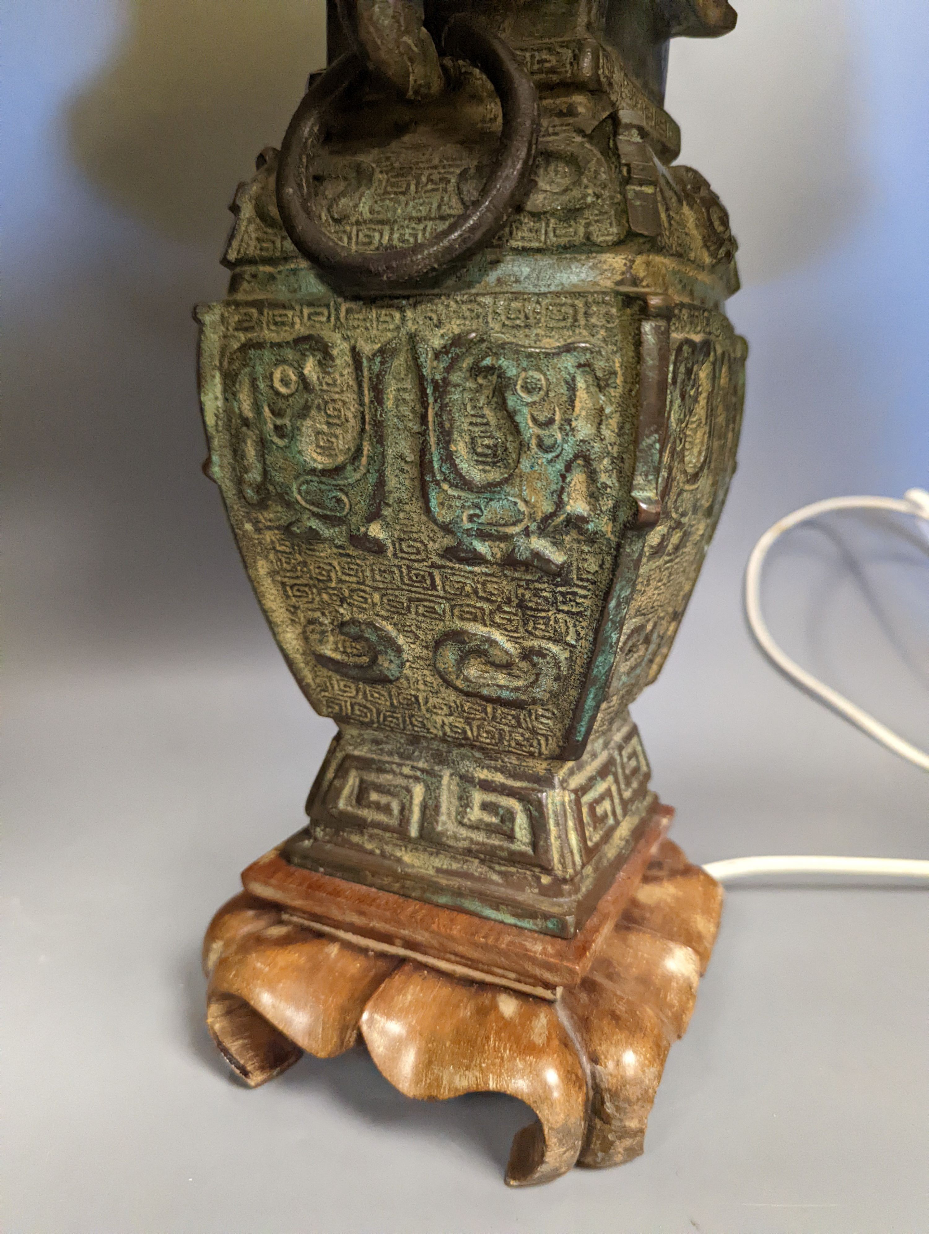 A pair of Chinese archaistic bronze lamps, 37 cms high not including shades or light fitting.